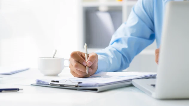 Rådgiver i arbeid med notater, dokumenter og laptop – strukturert planlegging og full kontroll på firmareiser fra et reisebyrå for bedrifter.